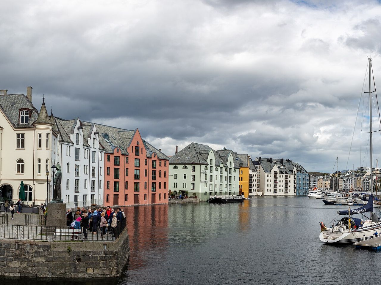 Pastel Art Nouveau buildings along the harbour channel in Ålesund under a grey sky