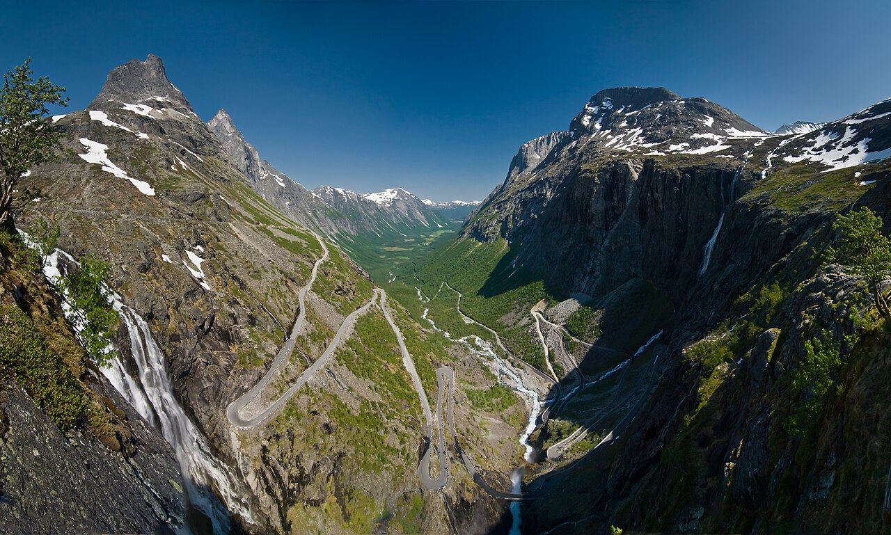 Looking down the hairpin bends of Trollstigen into a green valley between snow-flecked peaks